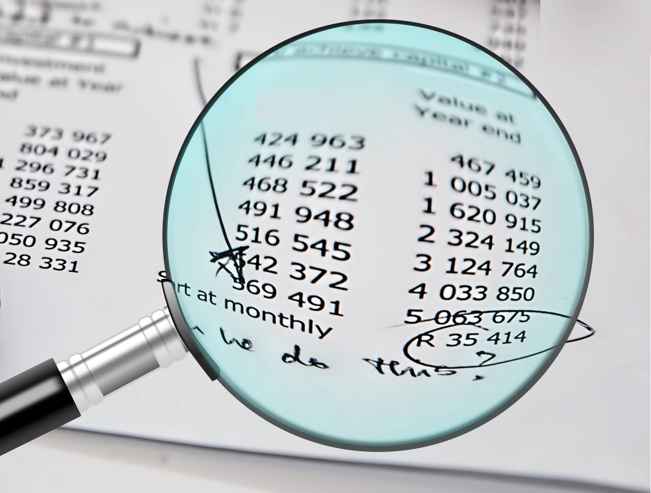 A magnifying glass showing two columns of numbers in accrual accounting.