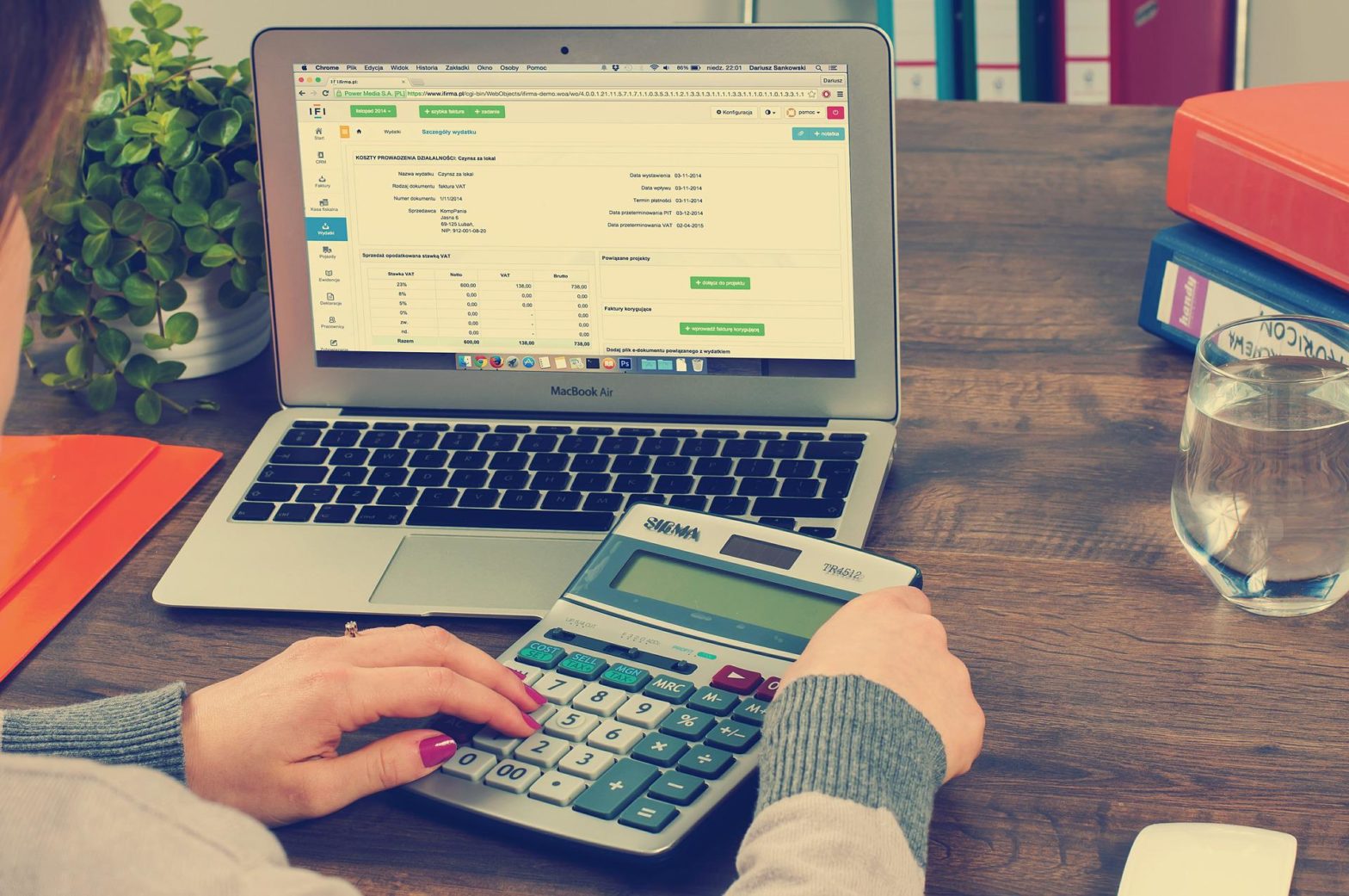 A woman offering online bookkeeping services with her calculator and laptop.