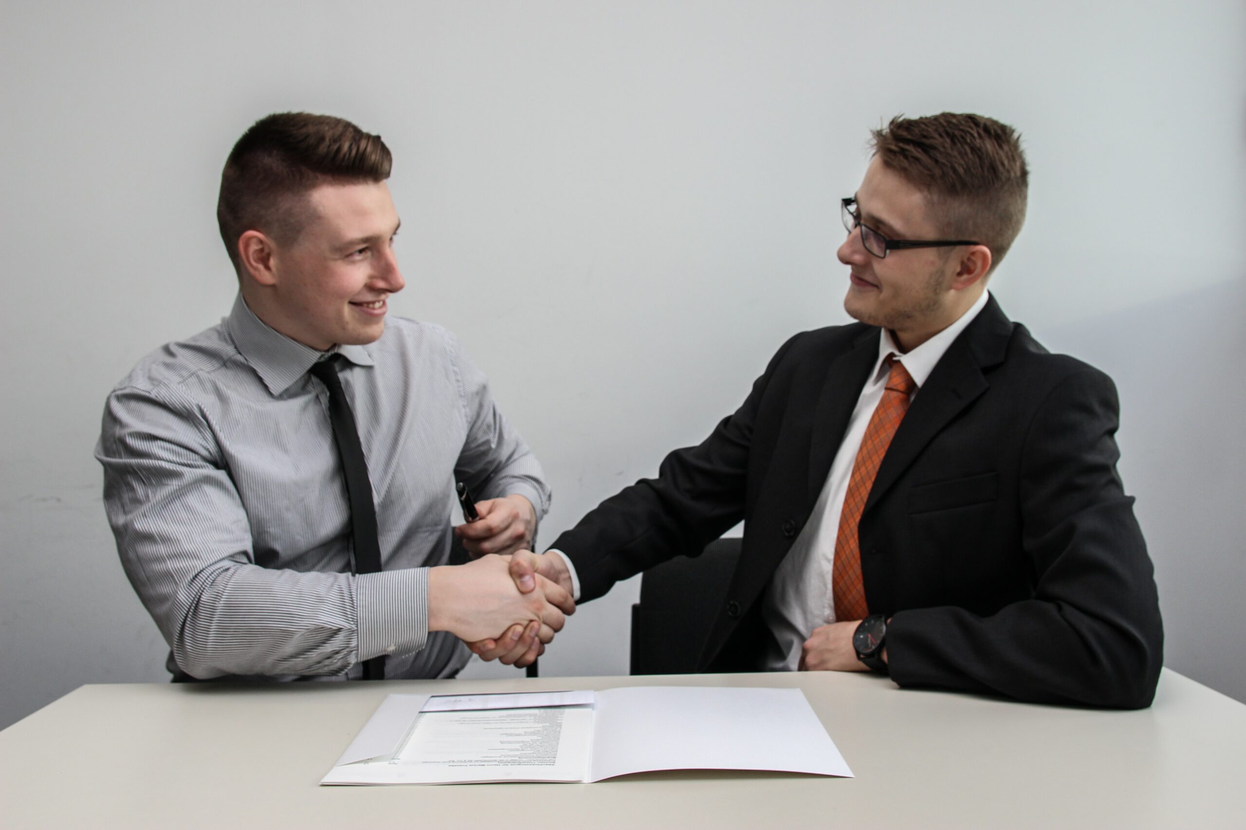 Two men shaking hands over some documents. bookkeeping interview questions