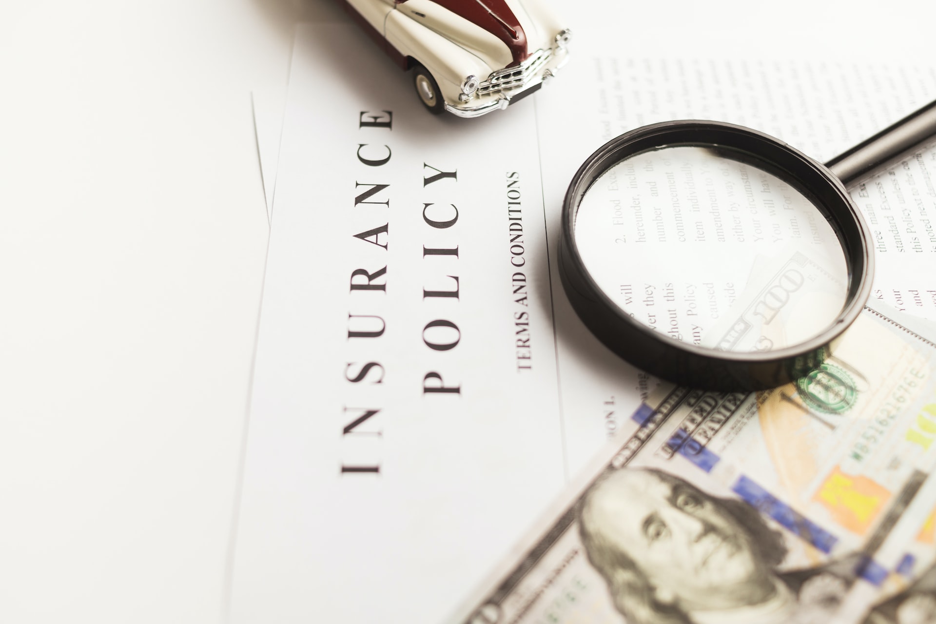 An eCommerce insurance policy with money, a magnifying glass, and a toy car on it.