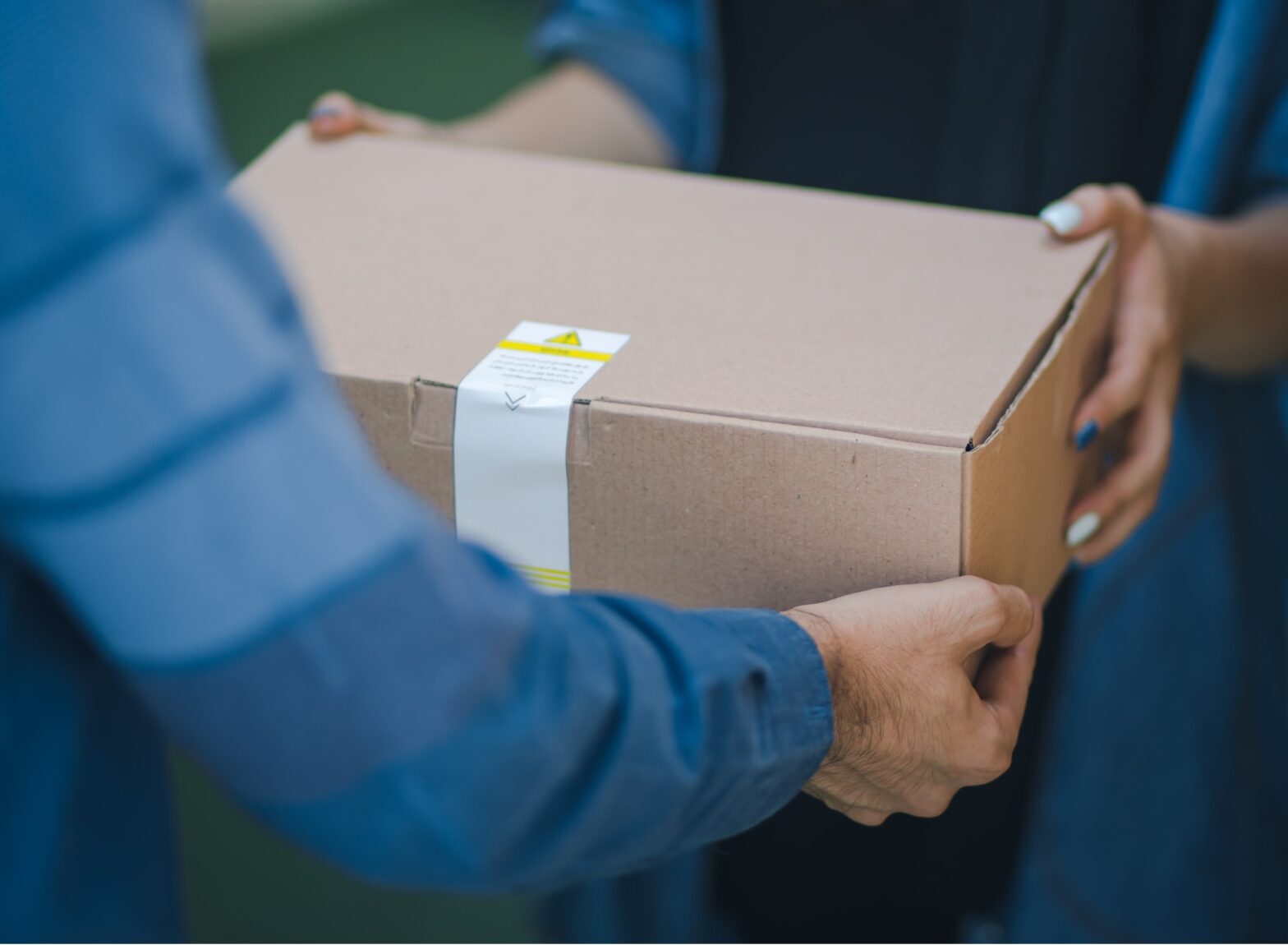 A man handing a box or mailed package to a woman.