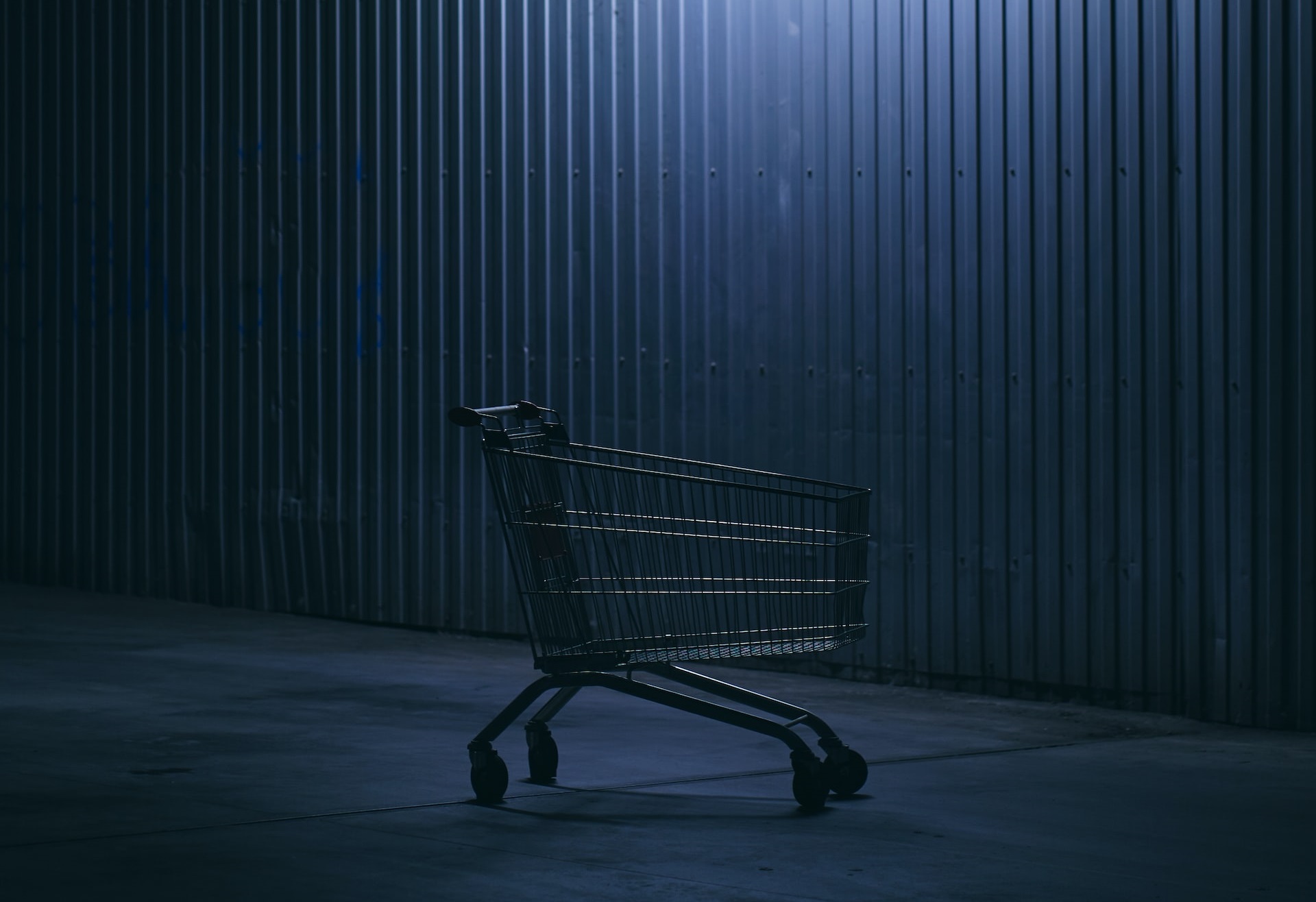 An abandoned shopping cart in a poorly lit area.