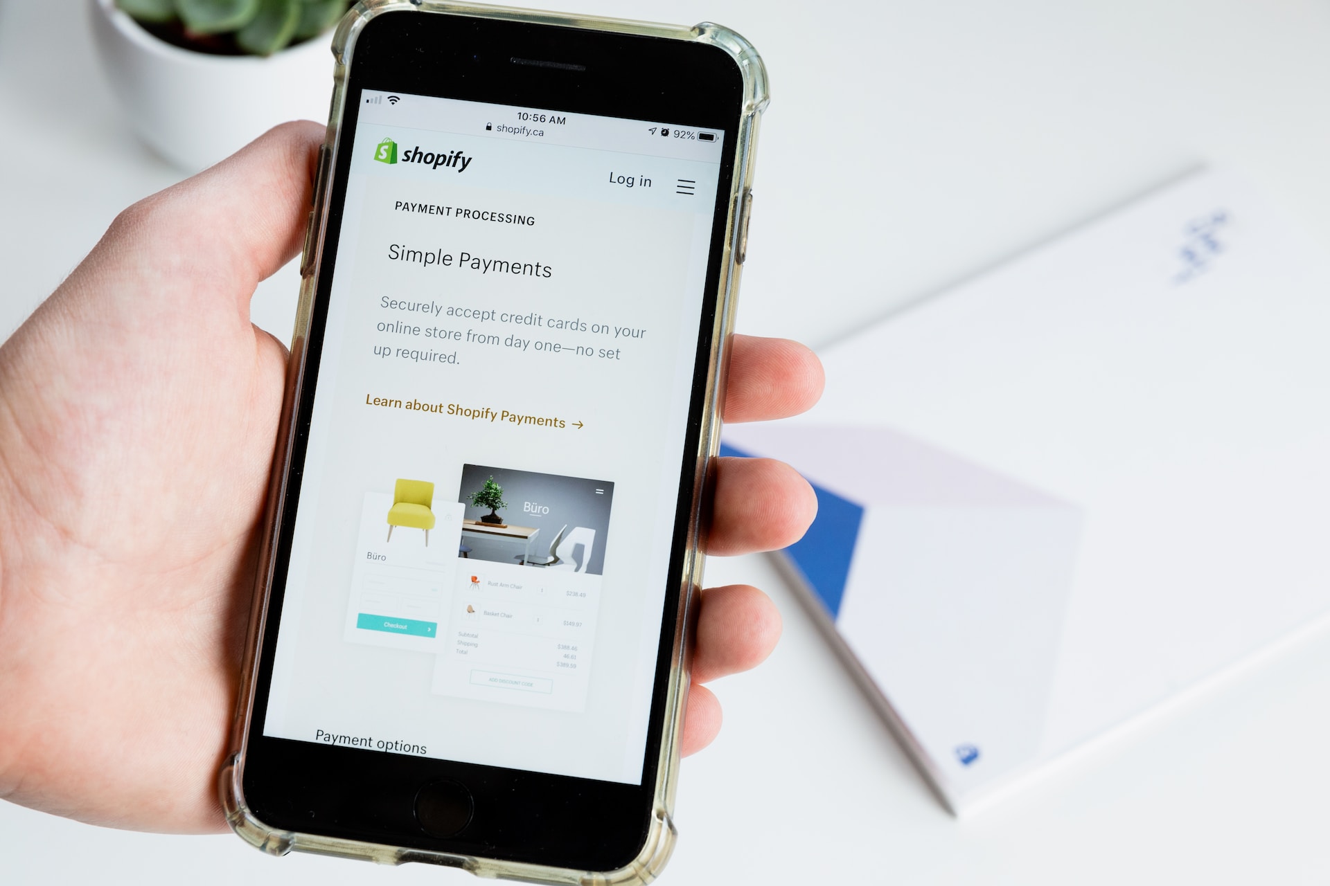 A hand holding a mobile phone showing Shopify tools for a store.