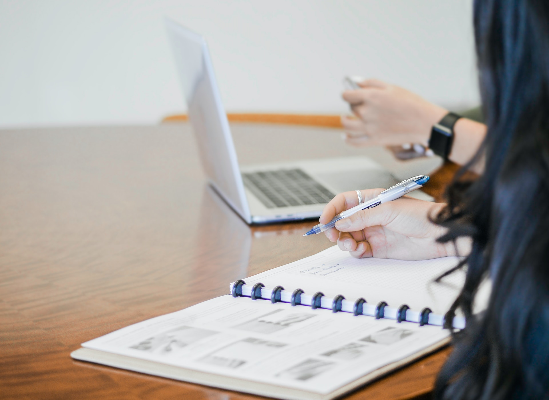 Women working on a laptop and a notebook on WooCommerce accounting software and WooCommerce accounting plugins