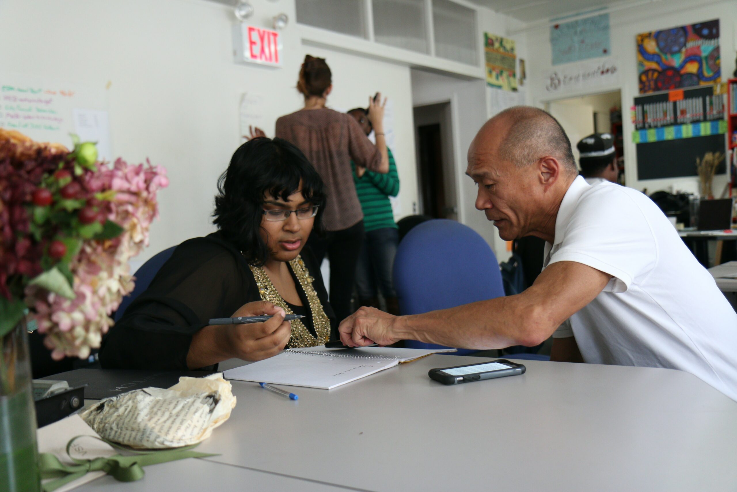 A man and a woman talking over documents at a table.