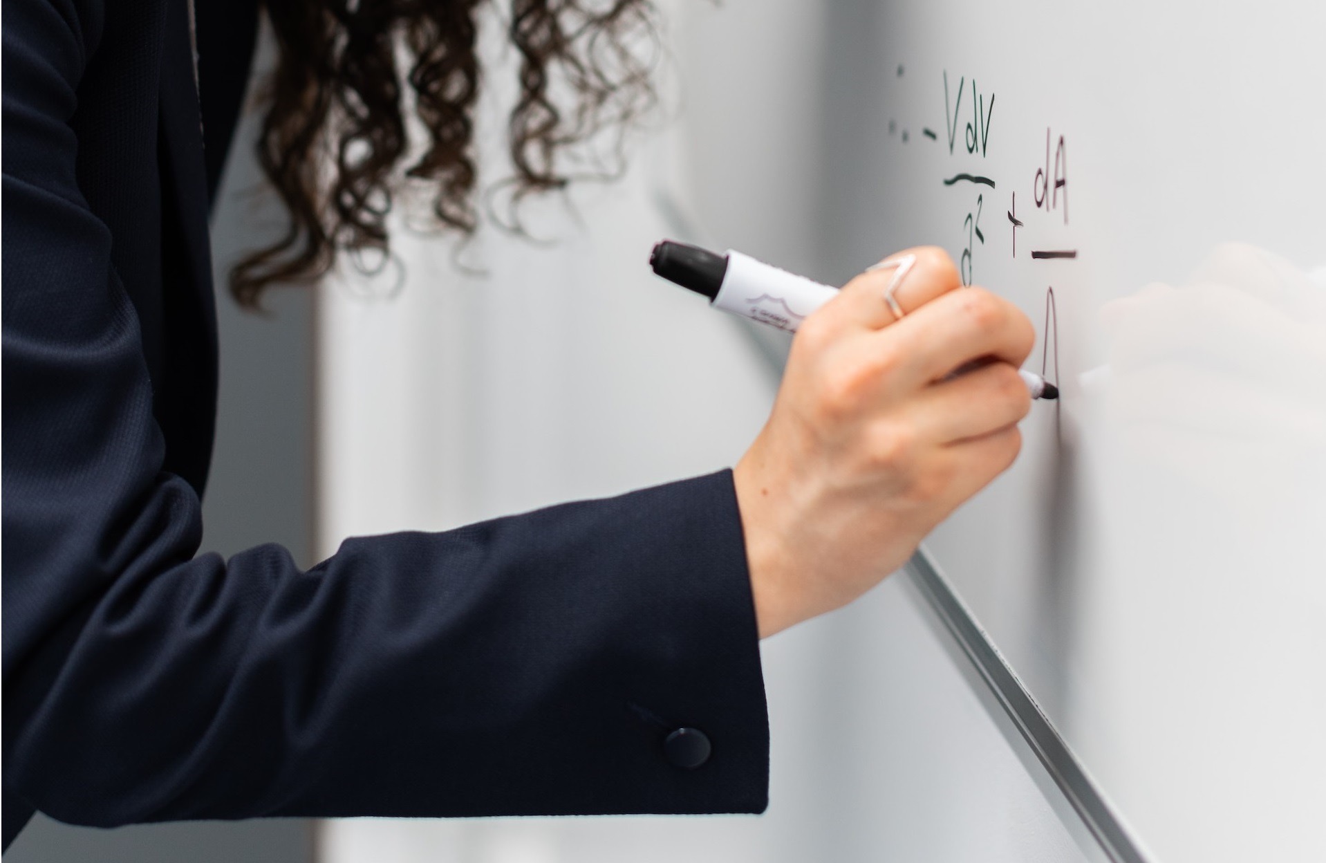 A woman writing a burn rate calculator formula on a whiteboard.