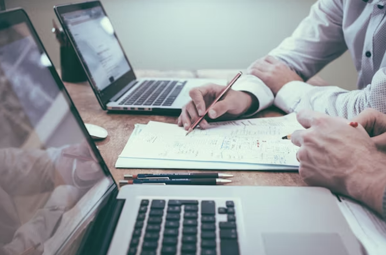 Two men with laptops looking over bookkeeping basics pdf.