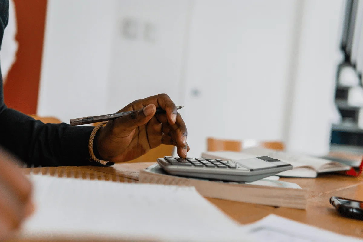 A person using a calculator while taking financial notes.