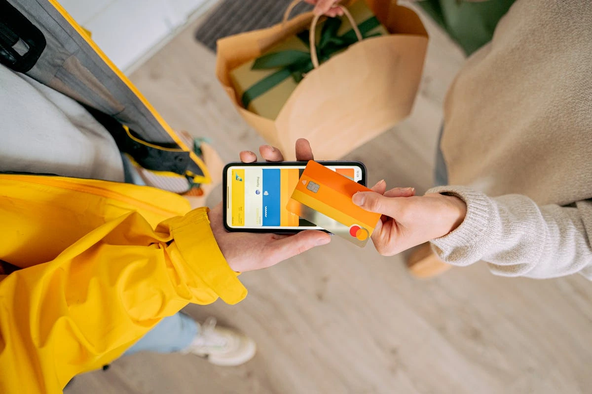 A person holding a smartphone in one hand and a credit card in the other, ready to make a purchase.