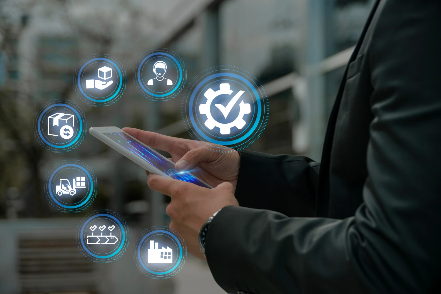 Man in a business suit holds a tablet displaying icons representing various business processes and workflows.