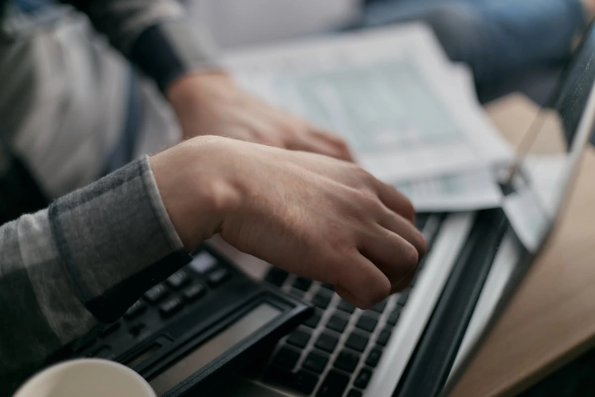 A person focused on typing on a laptop computer, with hands positioned over the keyboard.